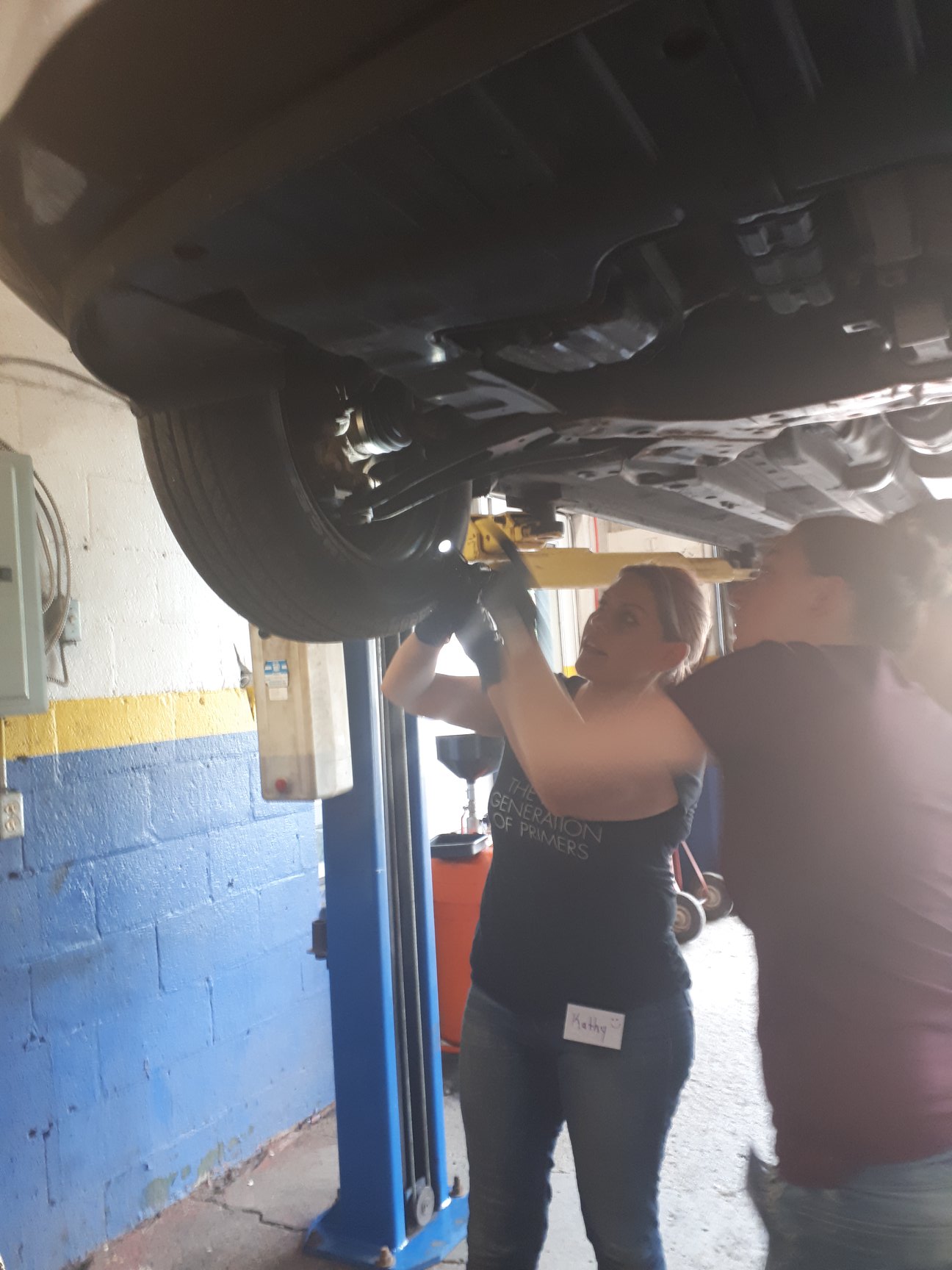 Two women working underneath a car