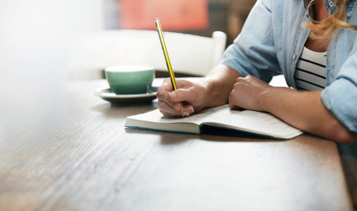 photo of women writing in a notebook. 